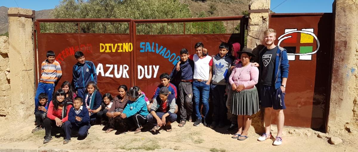 Das Bild zeigt eine Gruppe junger Menschen in Bolivien. Es ist ein Gruppenbild vor einem Tor.