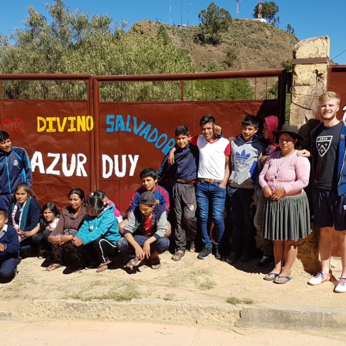 Das Bild zeigt eine Gruppe junger Menschen in Bolivien. Es ist ein Gruppenbild vor einem Tor.