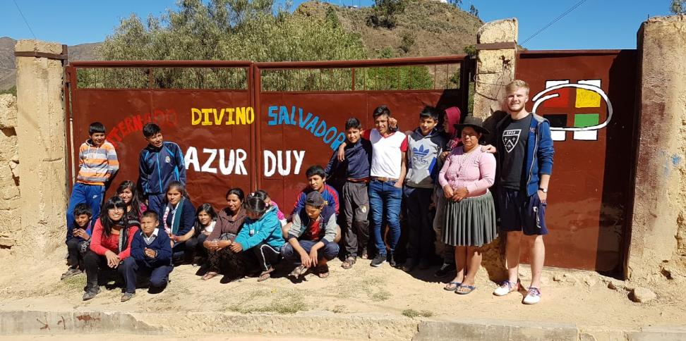 Das Bild zeigt eine Gruppe junger Menschen in Bolivien. Es ist ein Gruppenbild vor einem Tor.