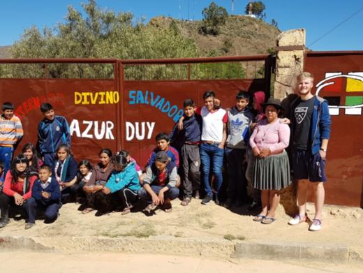 Das Bild zeigt eine Gruppe junger Menschen in Bolivien. Es ist ein Gruppenbild vor einem Tor.