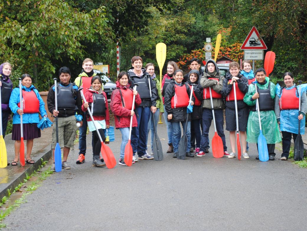 Das Bild zeigt eine Gruppe junger Personen. Alle halten Paddel in der Hand