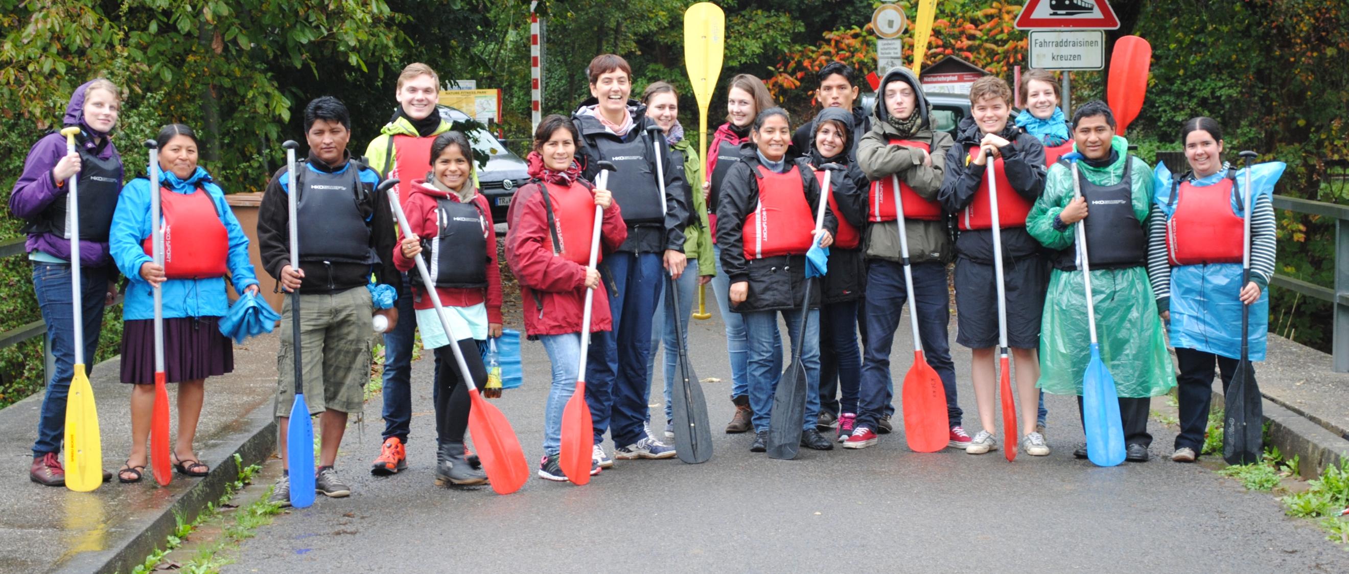 Das Bild zeigt eine Gruppe junger Personen. Alle halten Paddel in der Hand