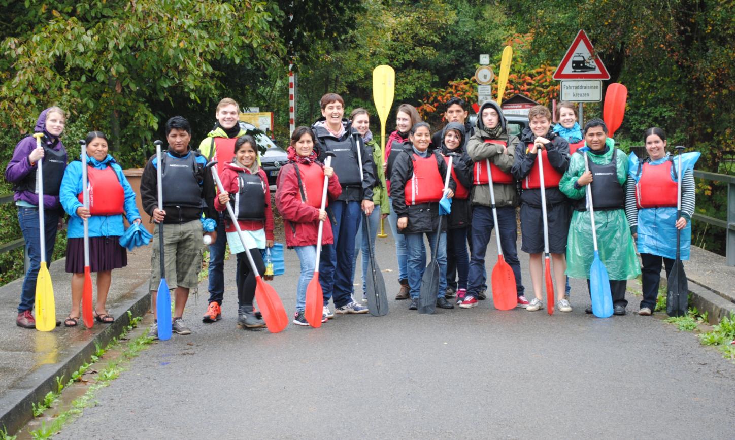 Das Bild zeigt eine Gruppe junger Personen. Alle halten Paddel in der Hand