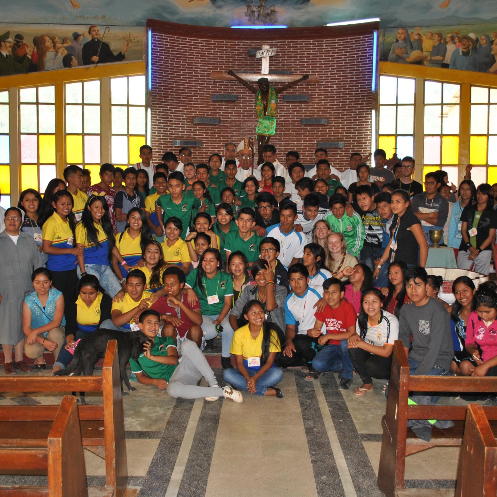 Das Bild zeigt eine Kirche in Bolivien, darauf ist eine große Gruppe von Personen vorm Altar