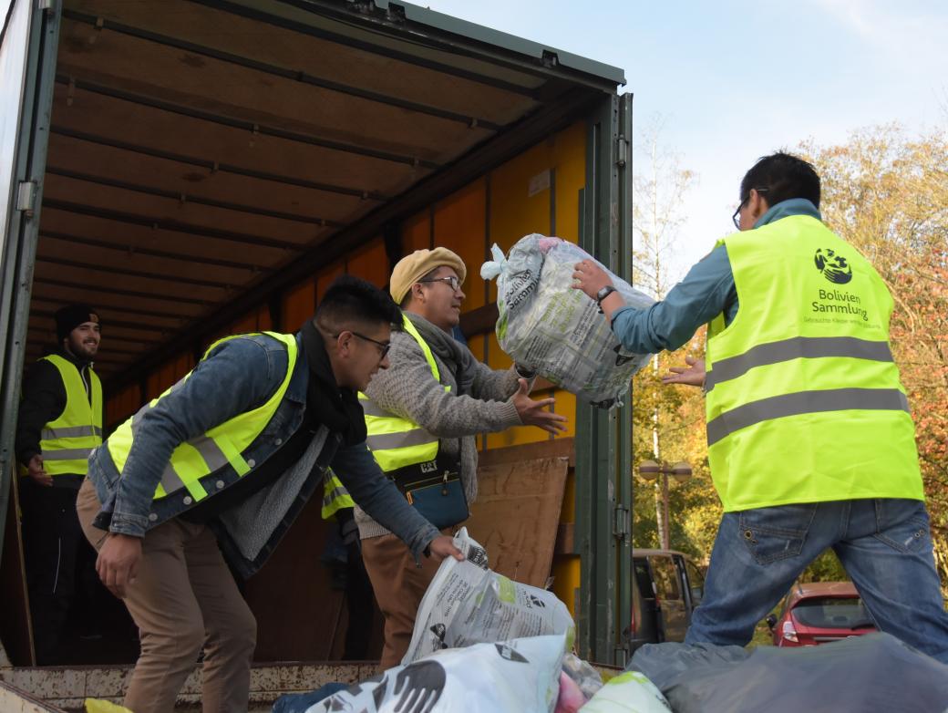 Das Bild zeigt Jugendliche beim Einladen von Kleidersäcken in einen LKW