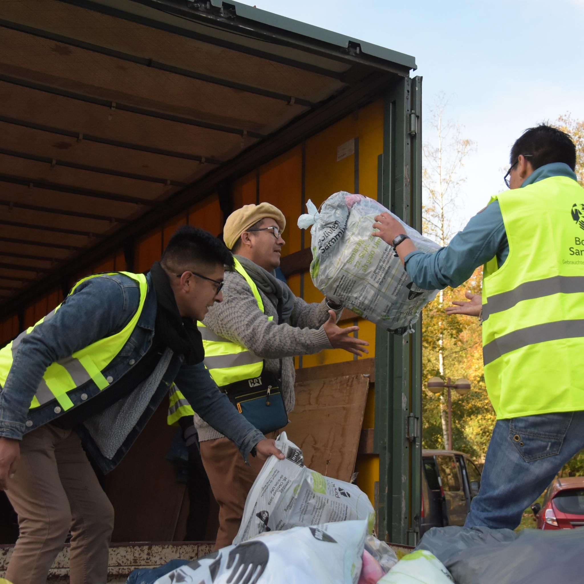Das Bild zeigt Jugendliche beim Einladen von Kleidersäcken in einen LKW