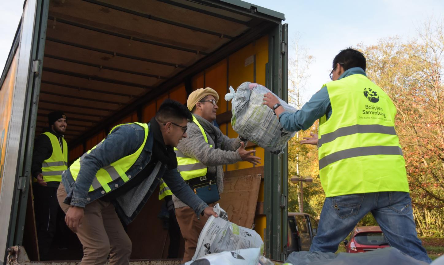 Das Bild zeigt Jugendliche beim Einladen von Kleidersäcken in einen LKW