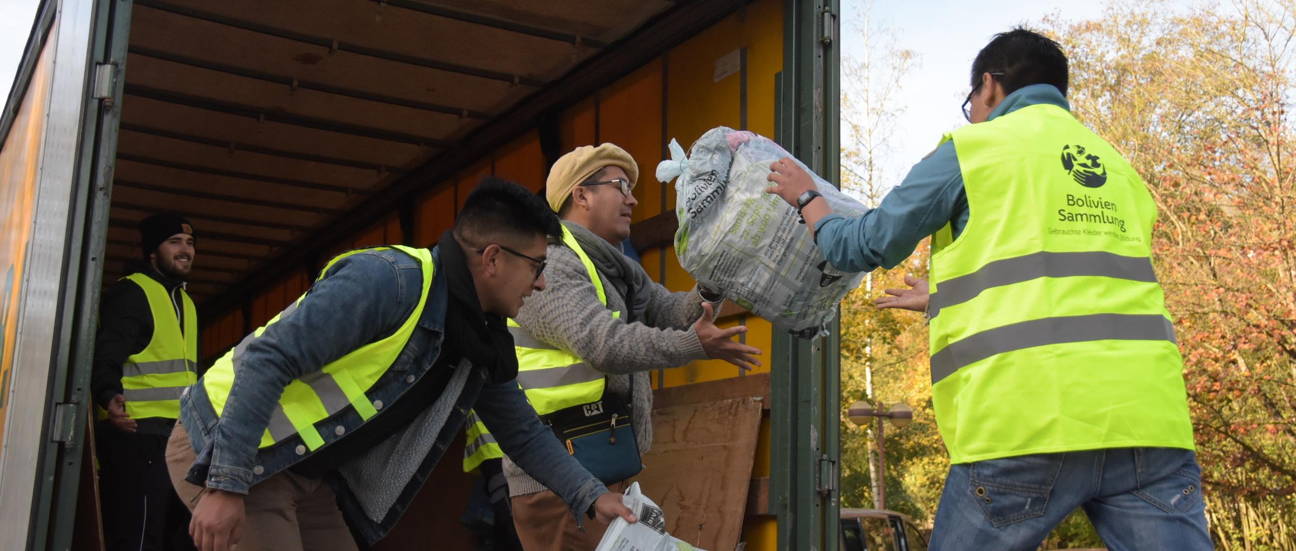 Das Bild zeigt Jugendliche beim Einladen von Kleidersäcken in einen LKW