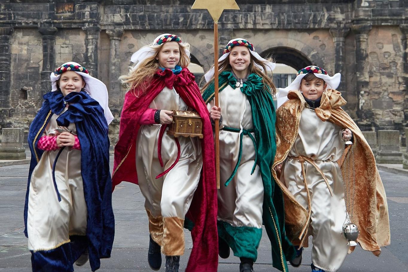 Das Bild zeigt vier Kinder als Sternsinger vor der Porta Nigra in Trier.