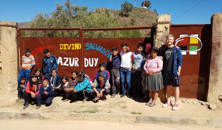Das Bild zeigt eine Gruppe junger Menschen in Bolivien. Es ist ein Gruppenbild vor einem Tor.