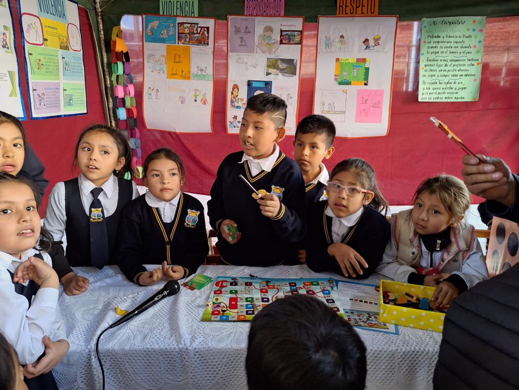 Das Bild zeigt Kinder in Bolivien in einer Schule. Im Hintergrund hängen von ihnen gestaltete Plakate