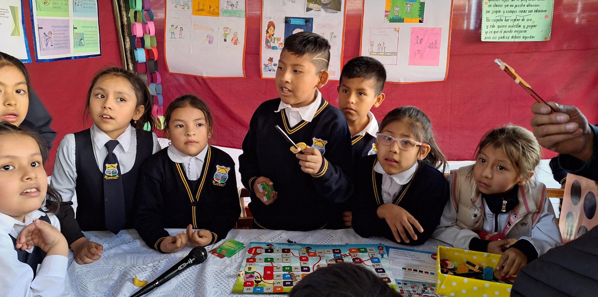 Das Bild zeigt Kinder in Bolivien in einer Schule. Im Hintergrund hängen von ihnen gestaltete Plakate
