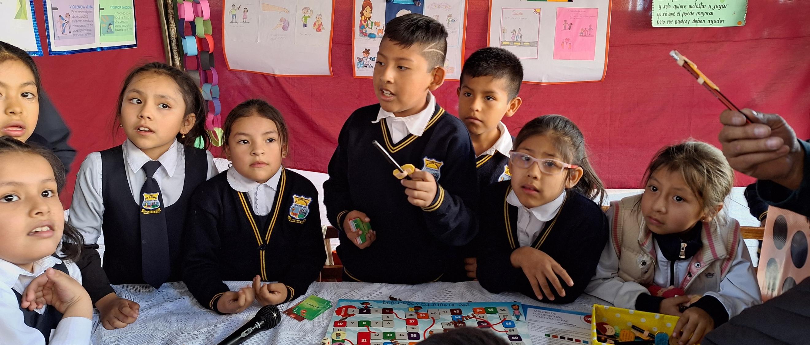 Das Bild zeigt Kinder in Bolivien in einer Schule. Im Hintergrund hängen von ihnen gestaltete Plakate