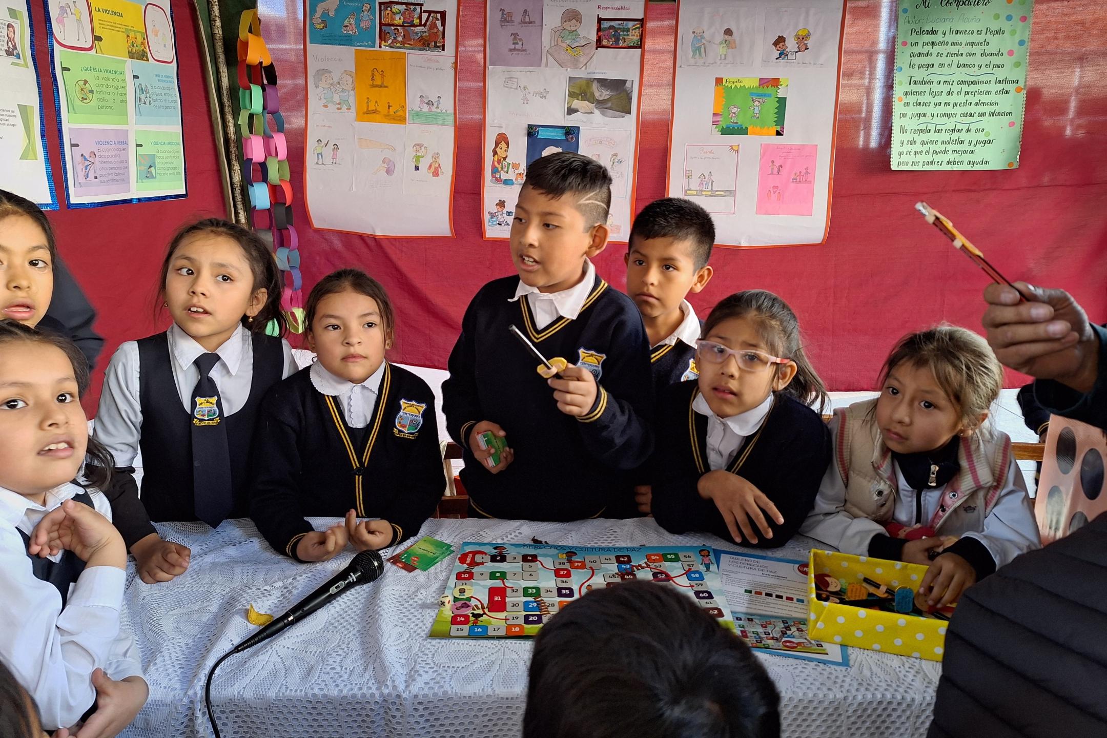 Das Bild zeigt Kinder in Bolivien in einer Schule. Im Hintergrund hängen von ihnen gestaltete Plakate