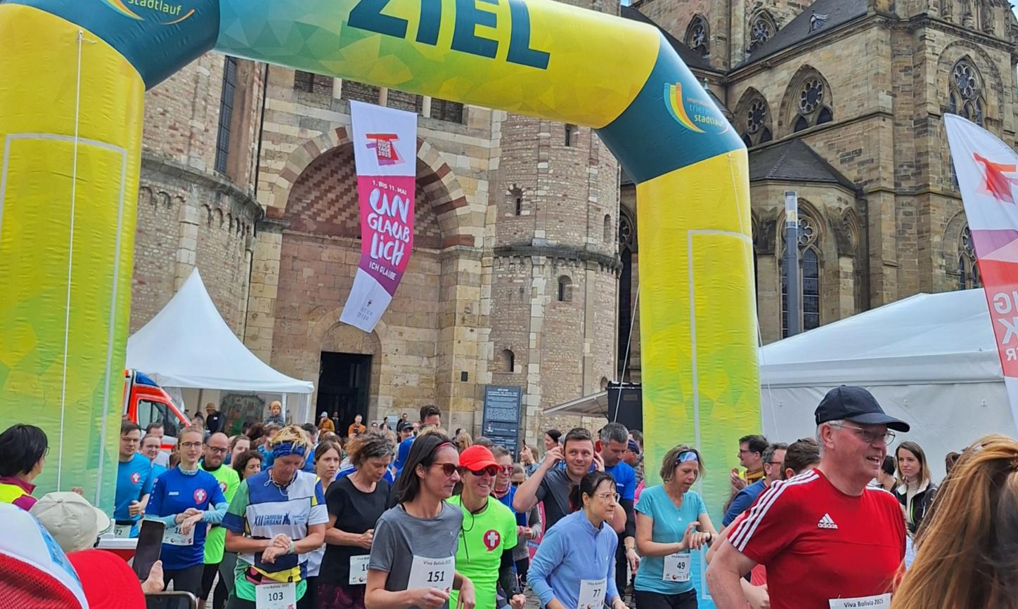 Das Bild zeigt das Ziel eines Spendenlaufes vor dem Trierer Dom. Man sieht viele Läufer.