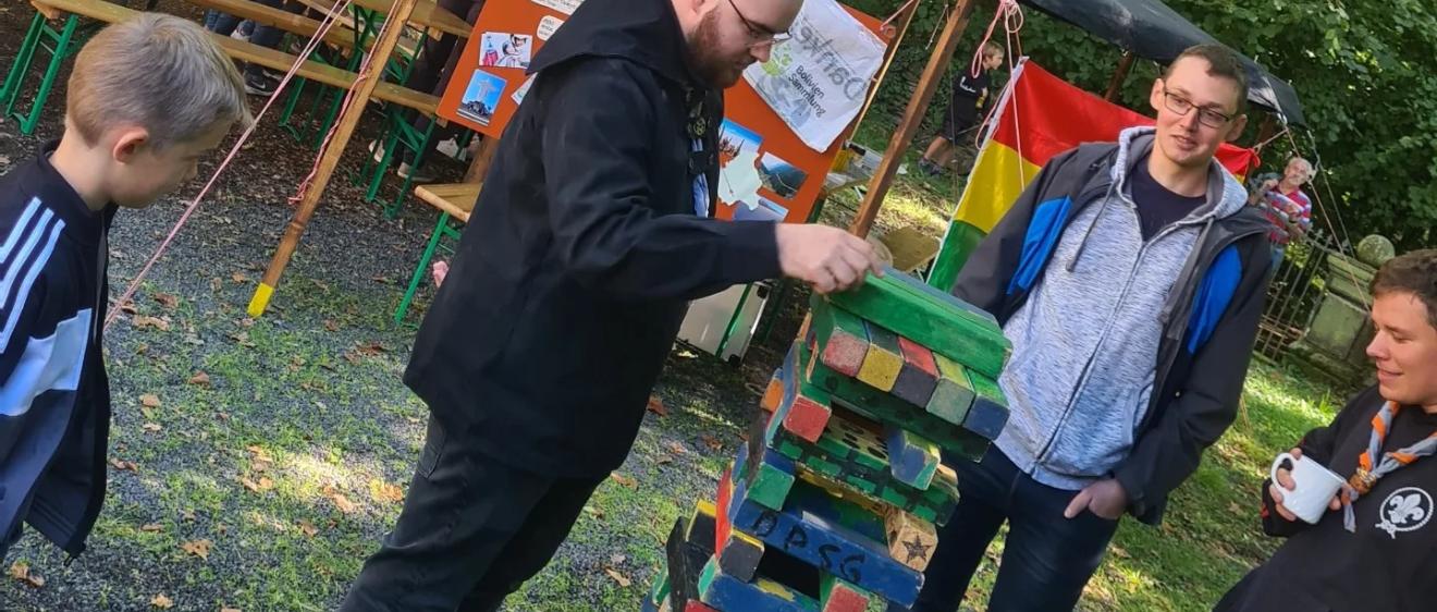 Das Bild zeigt einen Mann, dieser zieht einen Klotz bei einem Riesen-Jenga Spiel