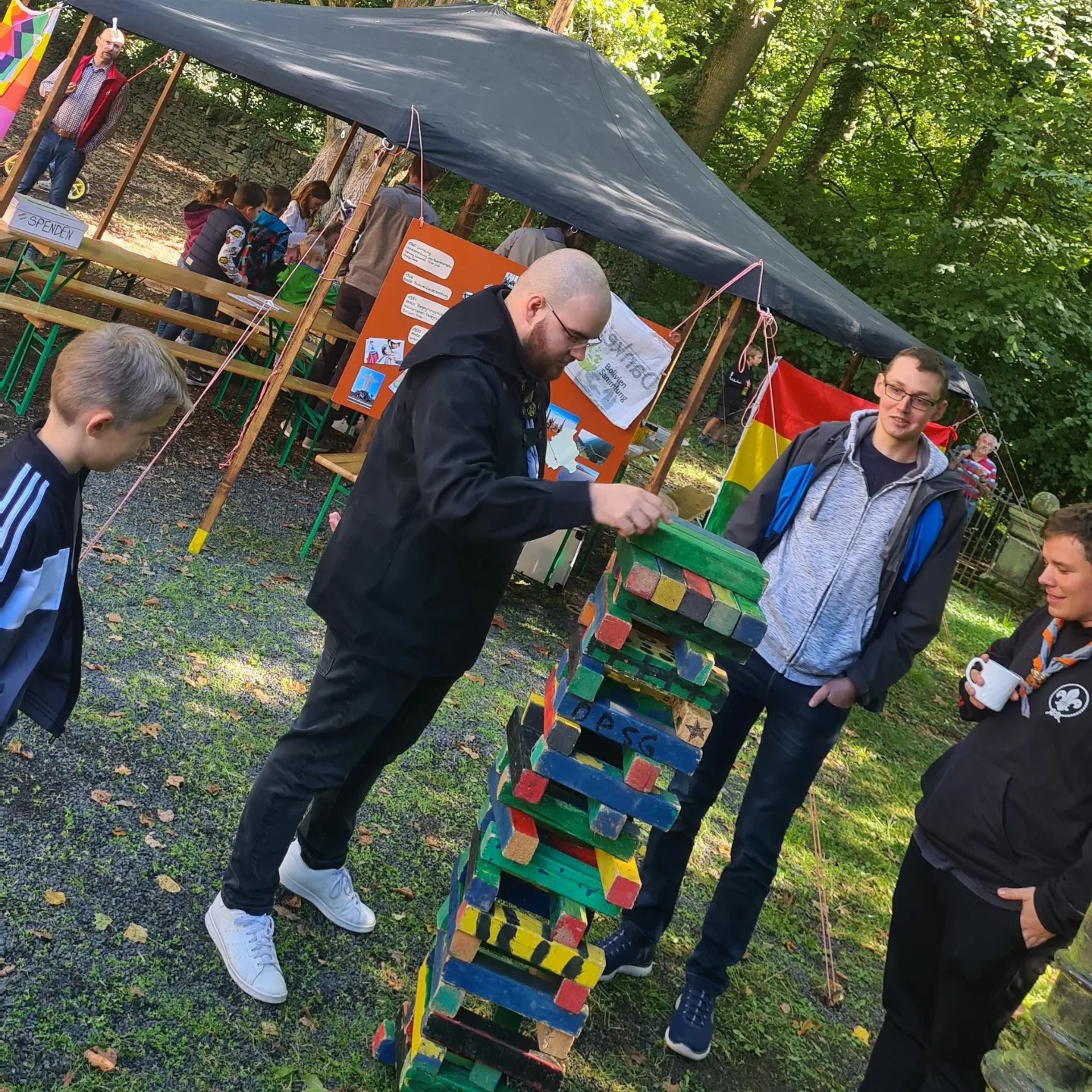 Das Bild zeigt einen Mann, dieser zieht einen Klotz bei einem Riesen-Jenga Spiel