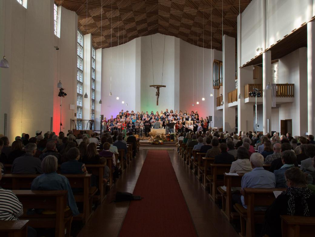 Das Bild zeigt von hinten einen Langen Shot in eine volle Kirche, während eines Benefizkonzertes