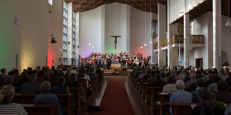 Das Bild zeigt von hinten einen Langen Shot in eine volle Kirche, während eines Benefizkonzertes