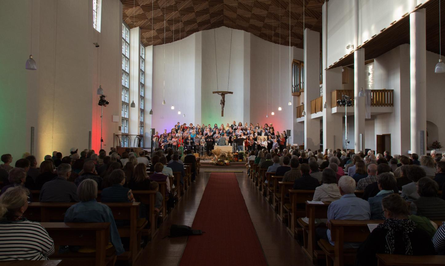 Das Bild zeigt von hinten einen Langen Shot in eine volle Kirche, während eines Benefizkonzertes