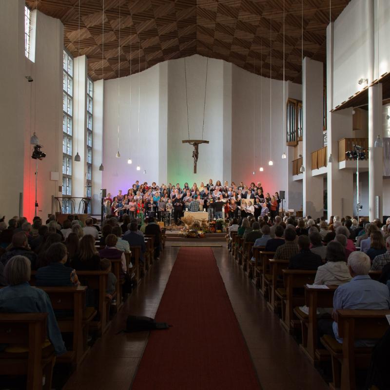 Das Bild zeigt von hinten einen Langen Shot in eine volle Kirche, während eines Benefizkonzertes