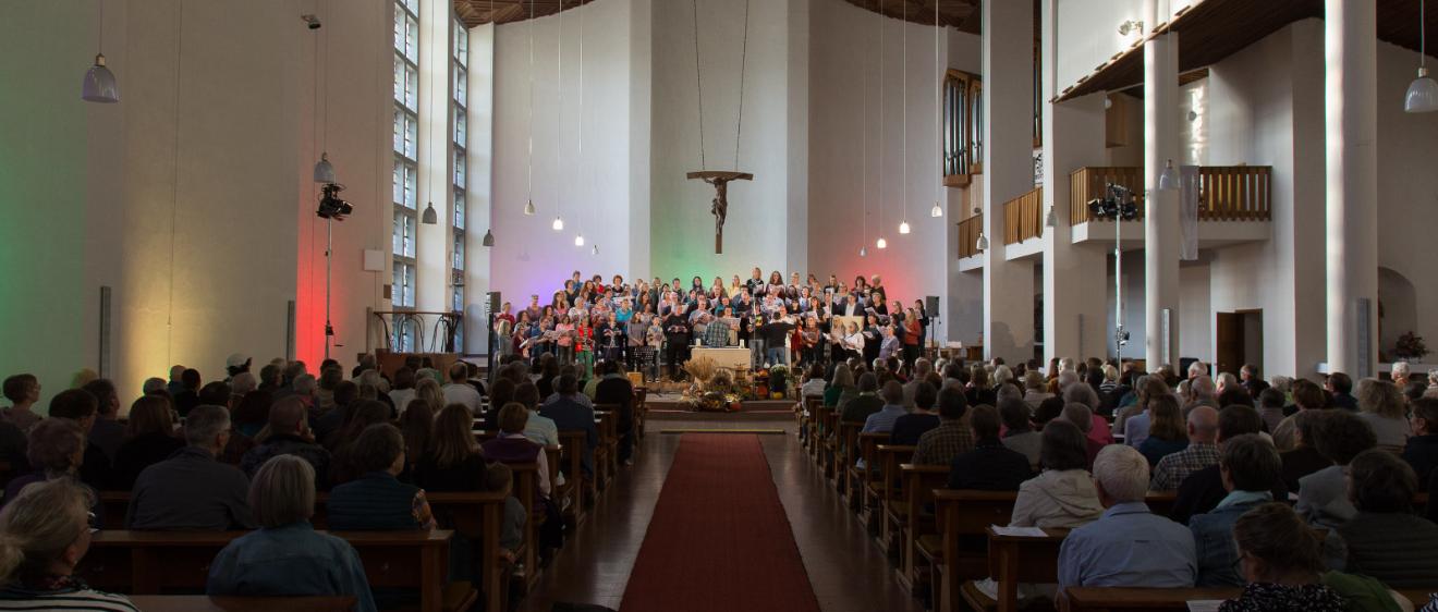Das Bild zeigt von hinten einen Langen Shot in eine volle Kirche, während eines Benefizkonzertes
