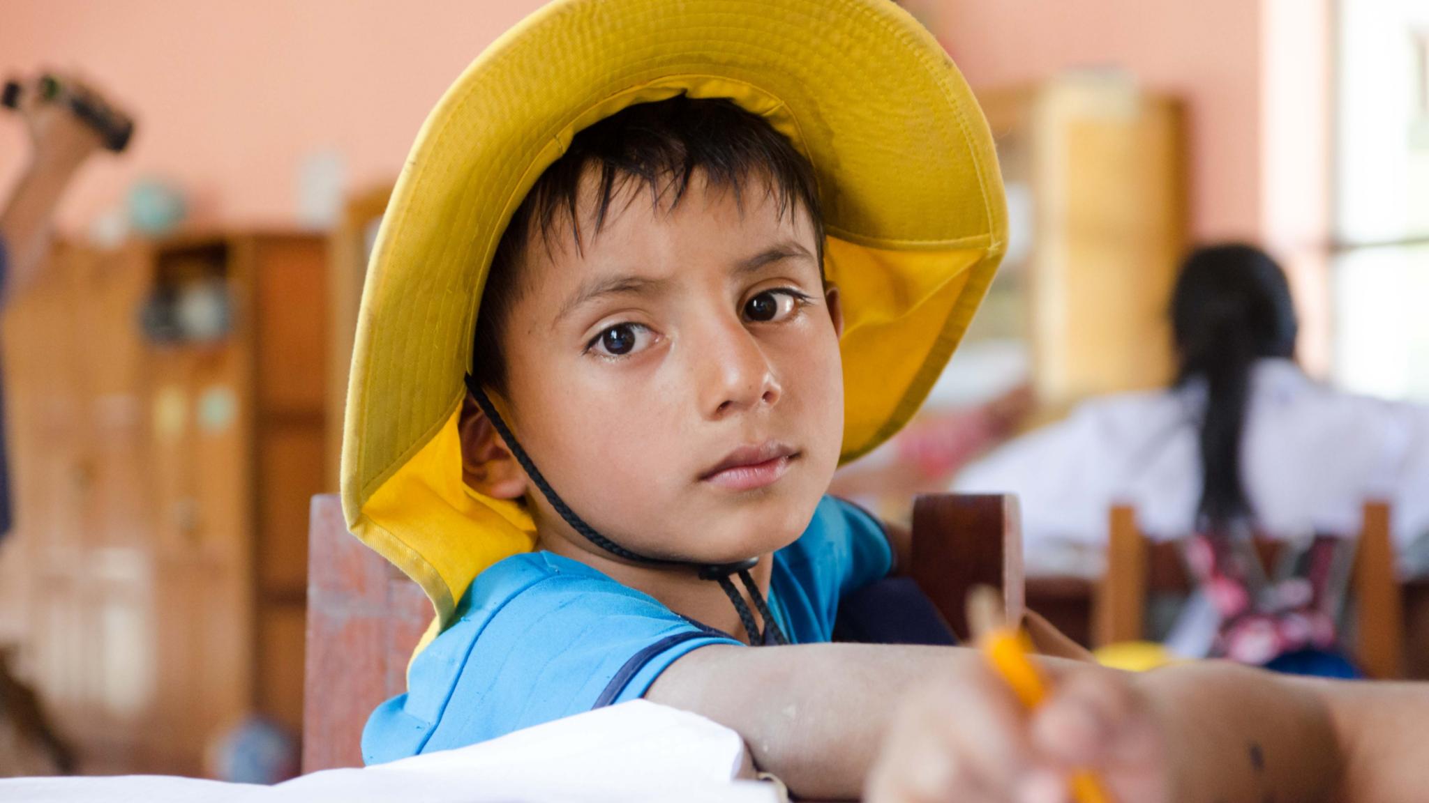 Ein Junge mit gelbem Hut schaut traurig in die Kamera