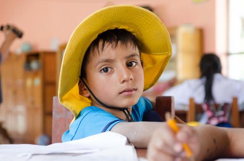 Ein junge mit gelbem Hut schaut traurig in die Kamera