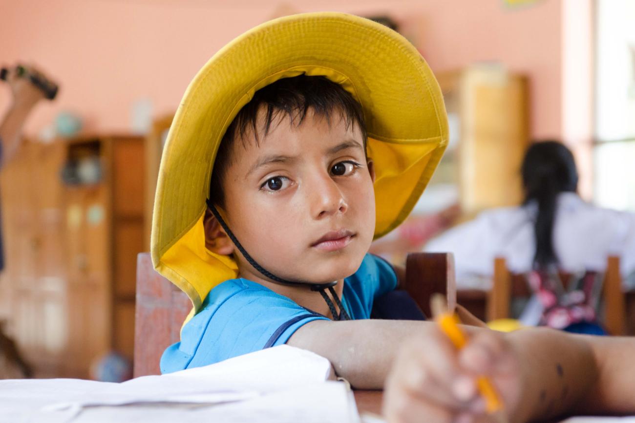 Ein Junge mit gelbem Hut schaut traurig in die Kamera
