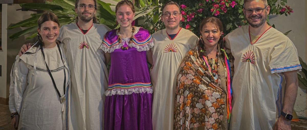 Das Bild zeigt sechs Menschen. Sie sind auf Begegnungsreise in Bolivien und tragen traditionelle Kleidung.