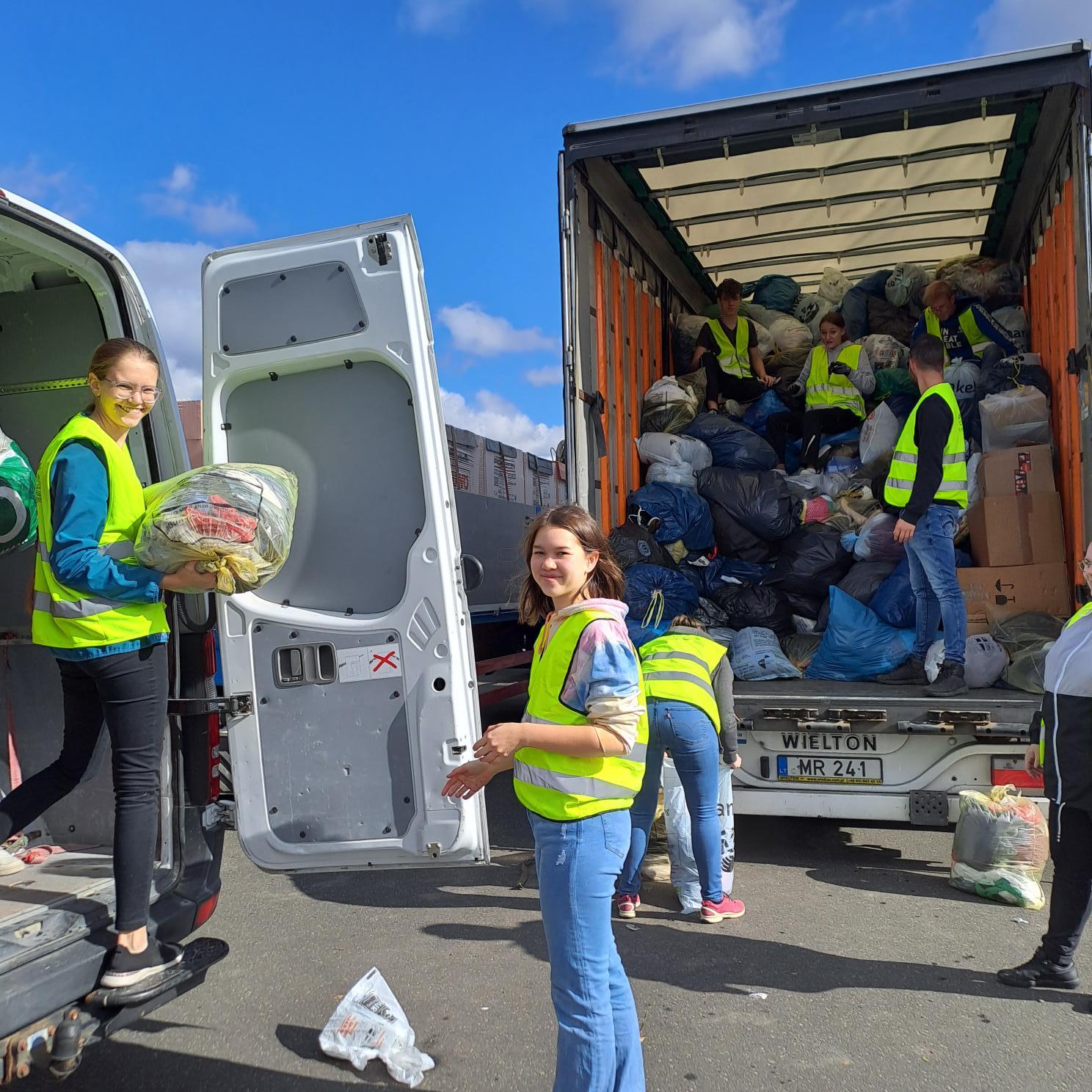 Das Bild zeigt Jugendliche welche Kleidersäcke in einen Sprinter und einen LKW einladen.