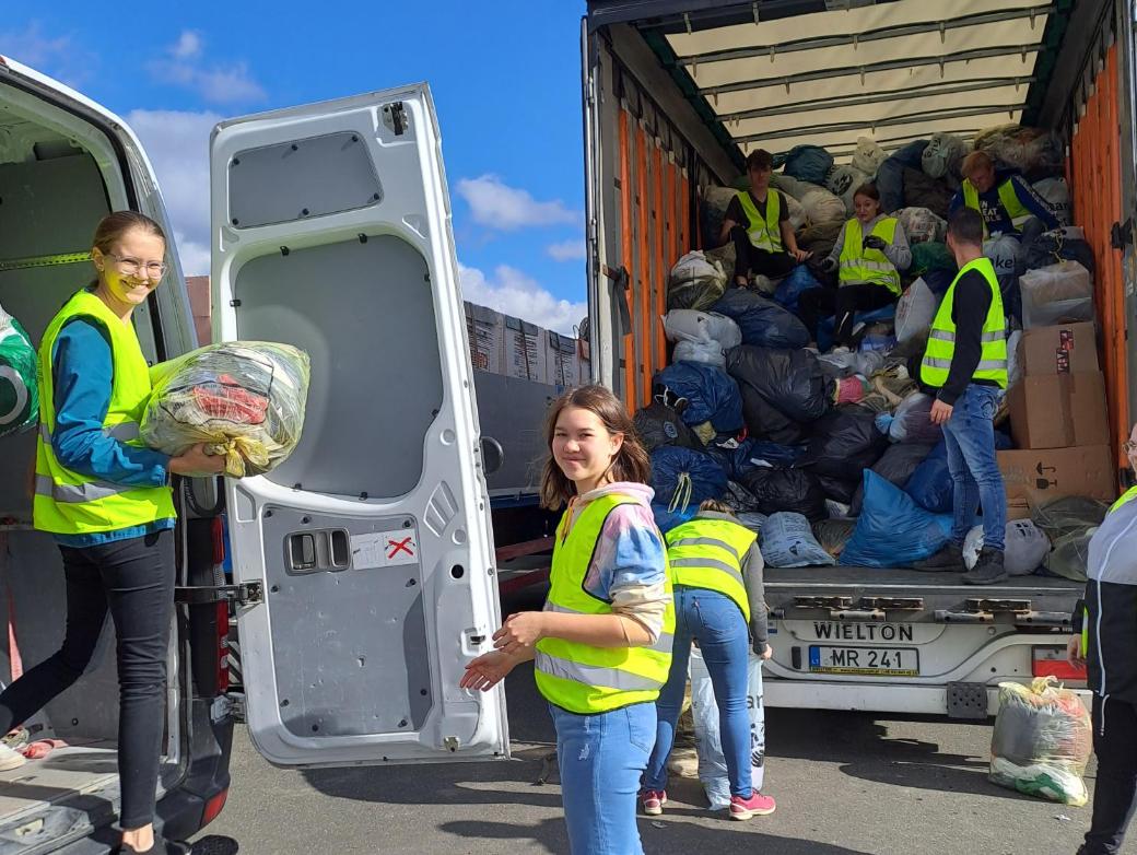 Das Bild zeigt Jugendliche welche Kleidersäcke in einen Sprinter und einen LKW einladen.