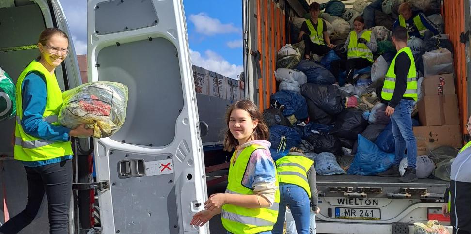 Das Bild zeigt Jugendliche welche Kleidersäcke in einen Sprinter und einen LKW einladen.
