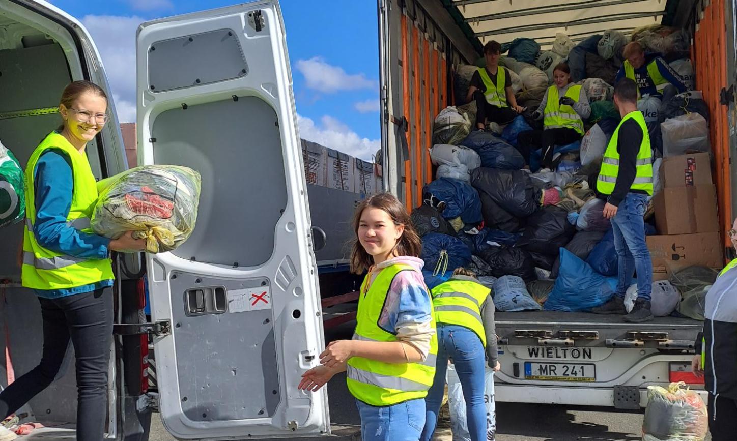 Das Bild zeigt Jugendliche welche Kleidersäcke in einen Sprinter und einen LKW einladen.