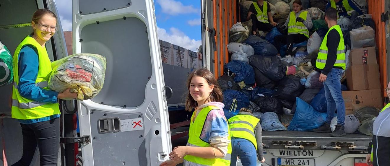 Das Bild zeigt Jugendliche welche Kleidersäcke in einen Sprinter und einen LKW einladen.
