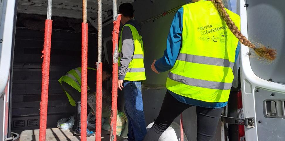 Das Bild zeigt zwei Personen die Säcke in einen Transporter laden