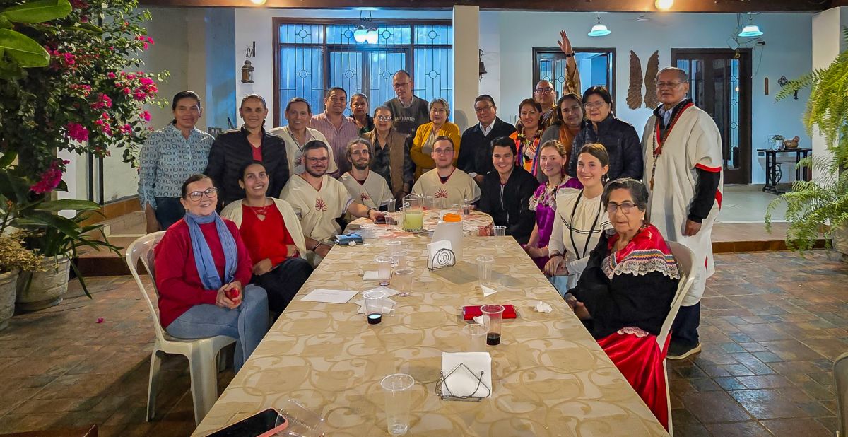 Das Bild zeigt einen langen Tisch. Am Ende versammelt sich eine Gruppe Menschen. Es ist ein Treffen der Begegnungsreise des Bistums Trier nach Bolivien.