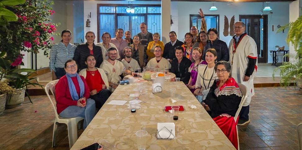 Das Bild zeigt einen langen Tisch. Am Ende versammelt sich eine Gruppe Menschen. Es ist ein Treffen der Begegnungsreise des Bistums Trier nach Bolivien.