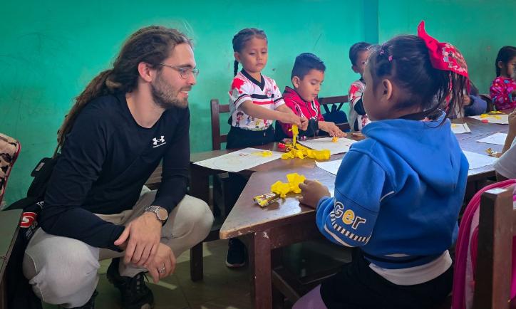 Das Bild zeigt einen Blick in eine Schulklasse in Bolivien. Kinder lernen an einem Tisch.
