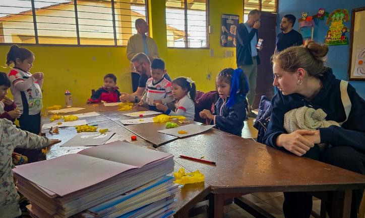 Das Bild zeigt einen Blick in eine Schulklasse in Bolivien. Eine Gruppe von Kindern lernt an Tischen.