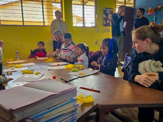 Das Bild zeigt einen Blick in eine Schulklasse in Bolivien. Eine Gruppe von Kindern lernt an Tischen.
