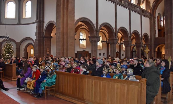 Das Bild zeigt eine große Gruppe von Sternsingern in der Kirche von vorne vom Altar weg fotografiert.