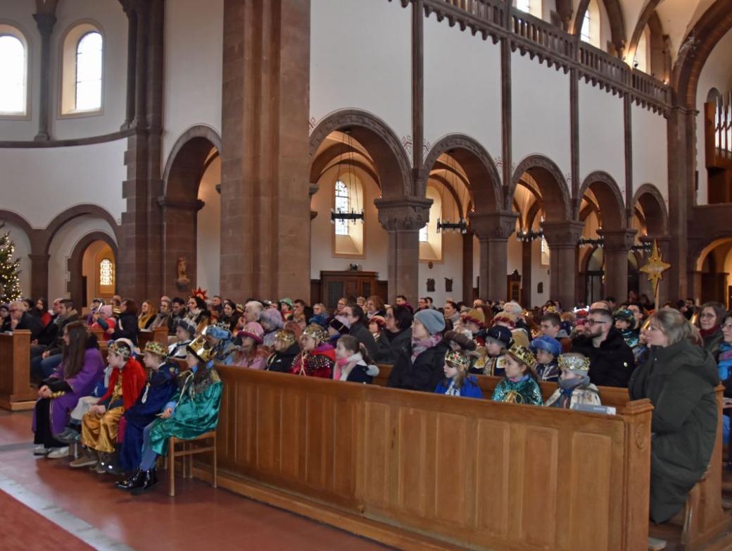 Das Bild zeigt eine große Gruppe von Sternsingern in der Kirche von vorne vom Altar weg fotografiert.