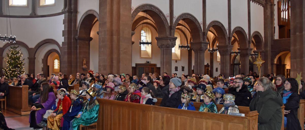 Das Bild zeigt eine große Gruppe von Sternsingern in der Kirche von vorne vom Altar weg fotografiert.
