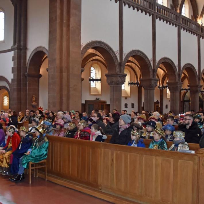Das Bild zeigt eine große Gruppe von Sternsingern in der Kirche von vorne vom Altar weg fotografiert.