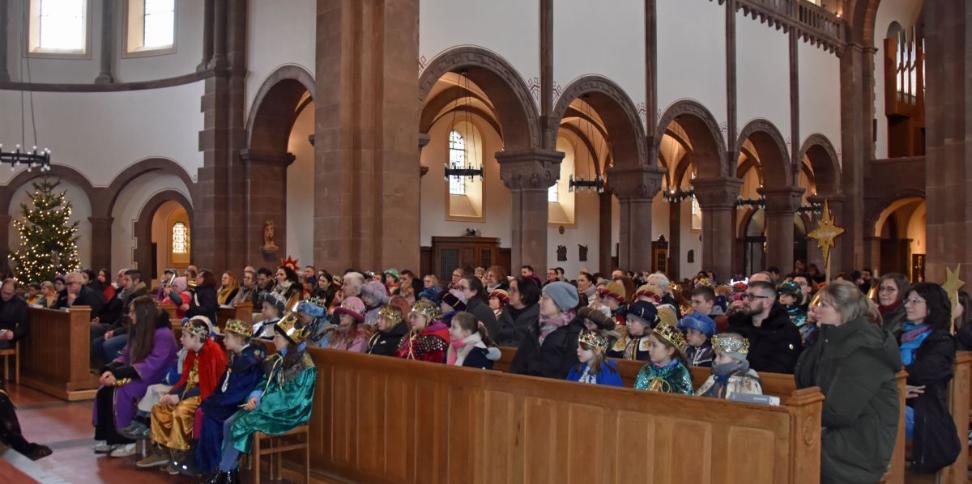 Das Bild zeigt eine große Gruppe von Sternsingern in der Kirche von vorne vom Altar weg fotografiert.