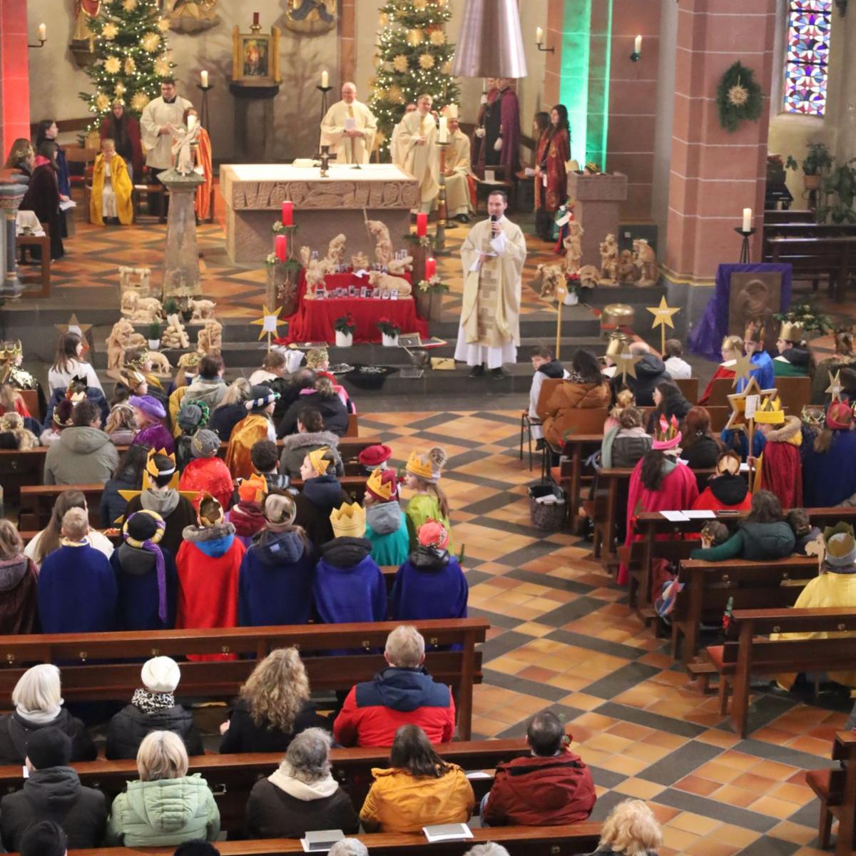 Das Bild zeigt eine große Gruppe von Sternsingern von oben/vom Eingang in Richtung Altar fotografiert.