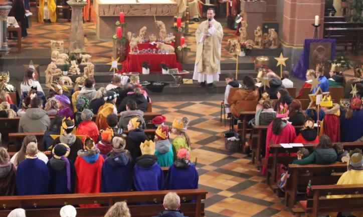 Das Bild zeigt eine große Gruppe von Sternsingern von oben/vom Eingang in Richtung Altar fotografiert.