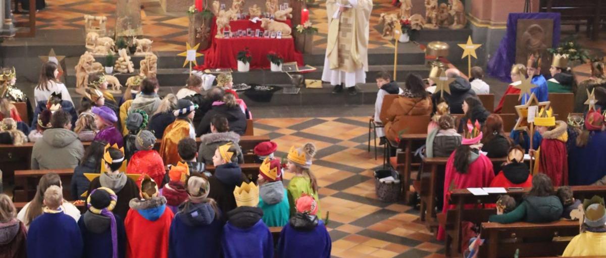 Das Bild zeigt eine große Gruppe von Sternsingern von oben/vom Eingang in Richtung Altar fotografiert.
