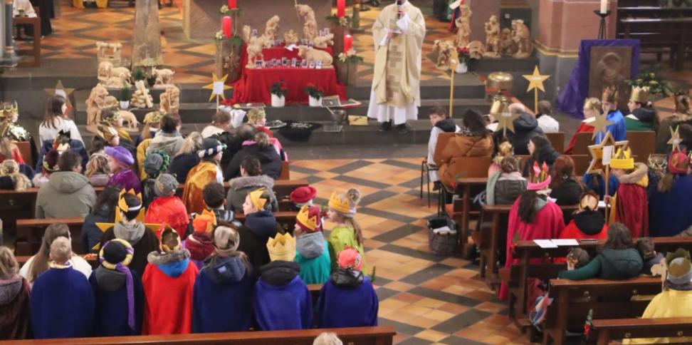 Das Bild zeigt eine große Gruppe von Sternsingern von oben/vom Eingang in Richtung Altar fotografiert.